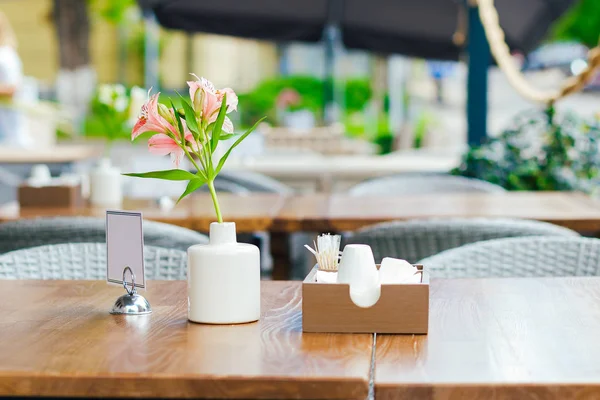 Vase with decorative flowers on the tables of outdoor street cafe. — Stock Photo, Image