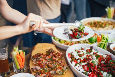 Kadınların elleri kendilerini tabakta yemek bir yemek kazık. Beslenme kavramı. Açık büfe. Gıda. Akşam yemeği. Paylaşımı kavramının.