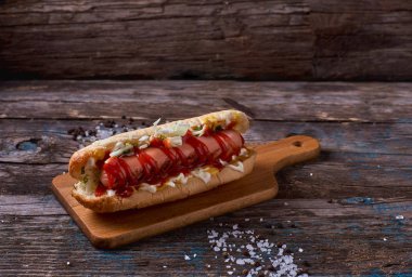 Evde yapılan sosisli sandviç domates, biber turşusu rustik ahşap arka plan üzerinde ahşap seving gemide