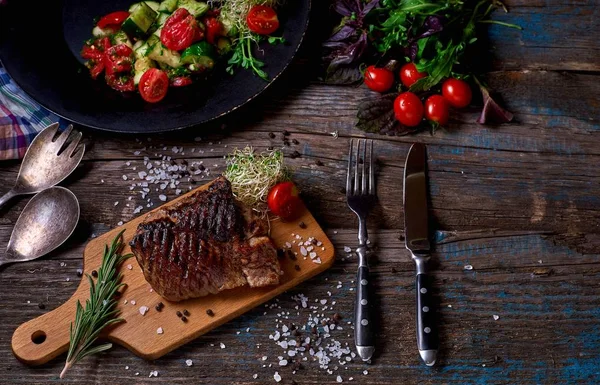 Renkli sebze, savory soslar ve tuz ile bir ülke steakhouse bir rustik ahşap sayaçta ızgara biftek servis havai görünümü