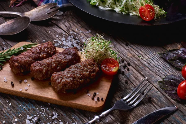 Produk panggangan: steak, sosis dan sayuran di atas meja kayu pedesaan. Sosis pada wajan panggangan di latar belakang kayu. Horisontal ruang fotokopi. Tampilan atas . — Stok Foto