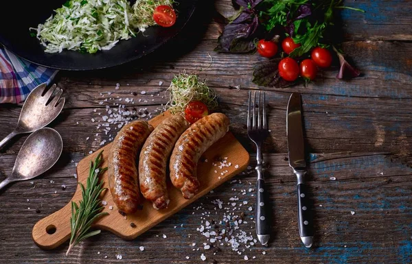 Vedere de sus a culorilor cârnați prăjiți și legume pe o masă de lemn rustic. Cârnați pe tigaia de grătar de pe fundalul din lemn. Privire de sus . — Fotografie, imagine de stoc