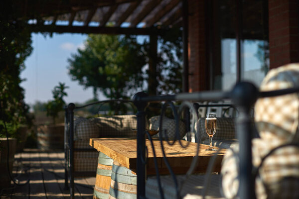 Cozy terrace with sofas for rest, Glass with champagne on a wooden table.