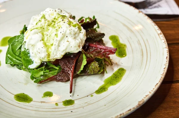 Especialidad italiana tradicional Queso Burrata en plato de cerámica servido con aceite de oliva y ensalada verde sobre una mesa de madera rústica blanca . — Foto de Stock