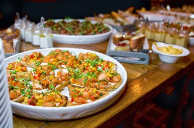 Bruschetta, meze ve farklı sos içeren tablo açık büfe. Humus, sığır eti, pate, avokado, domates ile. ahşap rustik masaya.