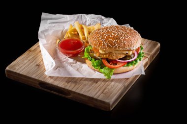 Burger siyah arka plan üzerine izole ahşap kesme tahtası üzerinde patates kızartması ile
