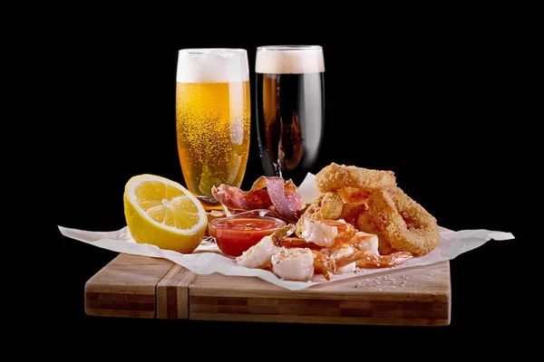Пивная закуска на деревянной доске с двумя бокалами пива на черном фоне. Закрыть — стоковое фото