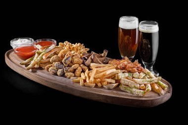 Çeşitli bira aperatifler. et, patates kızartması, tavuk kanatları, kraker, kızarmış parçalarını soslar iki bardak bira.
