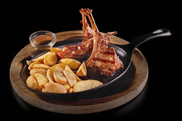 Las costillas fritas con las patatas y la cebolla en la sartén sobre la mesa rústica de madera. Enfoque cercano y selectivo — Foto de Stock