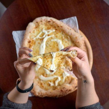 Yemek konsepti. İtalyan Pizza Lokantası Menüsü - Pizza Quattro formaggi pizza Bir dilim dilimle ayrılmış bir kadın eliyle.