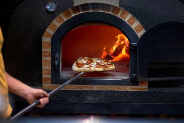 Yemek konsepti. Geleneksel İtalyan pizzasını hazırlıyorum. Fırının önünde fırında pizza..