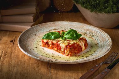 İtalyan mutfağı kavramı. Rustik ahşap masa üzerinde lezzetli pişmiş lazanya porsiyonu.