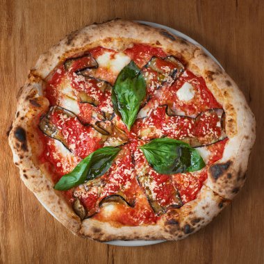 Geleneksel İtalyan pizzası patlıcan, mozzarella, fesleğen ve domatesli ahşap arka planda fotokopi alanı.