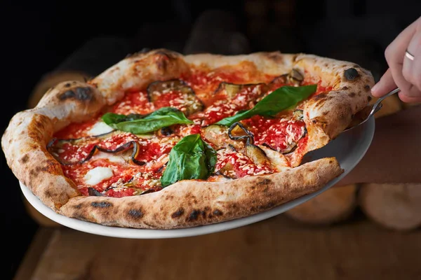 Traditionele Italiaanse pizza met aubergines, mozzarella, basilicum en tomaten op houten ondergrond — Stockfoto