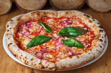 Köy mutfağında ahşap bir tahtanın üzerinde ton balıklı ve kırmızı soğanlı İtalyan pizzası ya da eski ahşap bir masada pizzacı.