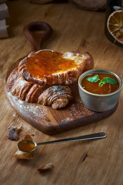 Croissant recién horneado con mermelada de albaricoque y mesa una cuchara de cerca sobre fondo de madera rústica — Foto de Stock