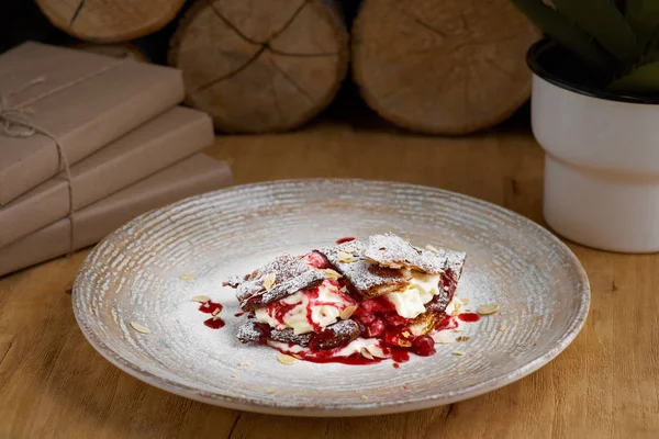 Frans dessert millefeuille van bladerdeeg en vla en ijs op een bord en op een houten tafel, close-up — Stockfoto