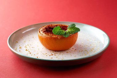 Kırmızı arka planda portakal ve badem sütlü krema ve nane şekeri, yakın plan.