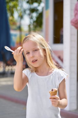 Dışarıda dondurma yiyen tatlı küçük kız. Ön plandaki kıza odaklan.