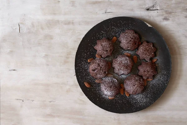 Dessert chocolade muffins op een zwarte plaat en een lichte houten ondergrond — Stockfoto