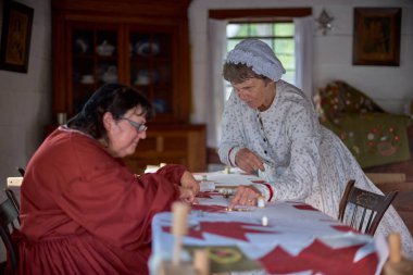 UPPER CANADA VILLAGE, MORRISBURG, ONTARIO, CANADA - 17 Ekim 2019: Aktörler Ontario Açık Hava Müzesi 'ndeki bir ortaçağ festivalinde sakinleri rolünü oynarlar. Olgun kadın terziler. Kanada 'ya seyahat.
