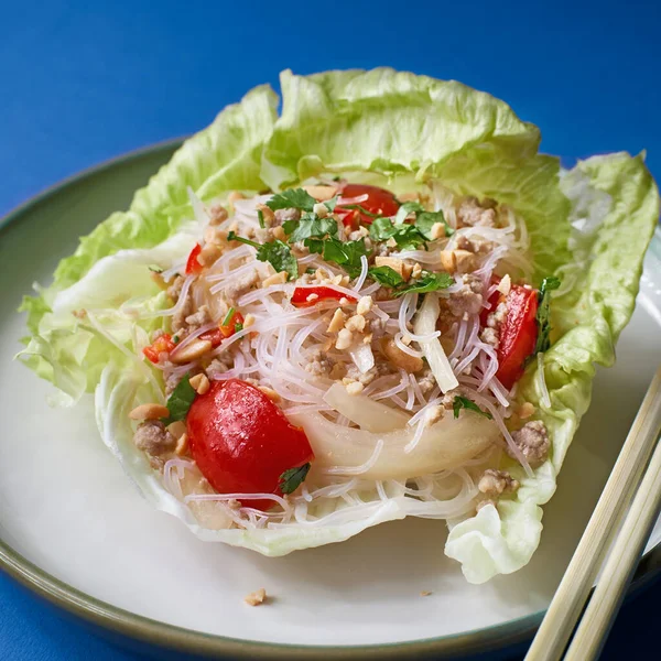 Chinese dishes for the new year. Rice noodles with vegetables salad in a dish. Blue background