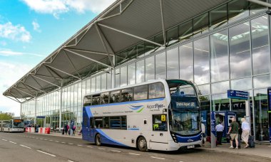 BRISTOL, ENGLAND - AUGUST 2019: Airport Flyer bus at a bus stop outside the terminal building at Bristol Airport. It is a shuttle service linking the airport and the city centre. clipart
