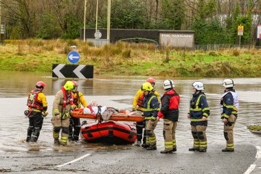 NANTGARW, NEAR CARDIFF, WALES - FEBRUARY 2020: Firemen carrrying an elderly lady on a stretcher from an inflatable boat after evacuation due to flooding in Nantgarw near Cardiff