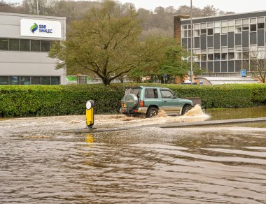 NANTGARW, NEAR CARDIFF, WALES - FEBRUARY 2020: Vehicle driving through flood water on Treforest Industrial Estate near Cardiff
