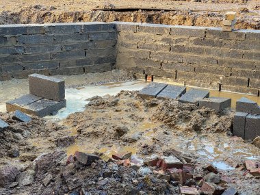 Bir bahçenin etrafındaki beton bloğun önündeki yıkıntı ve su birikintileri..