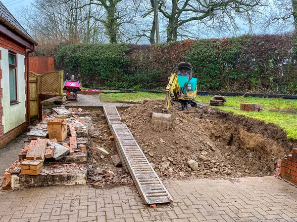 CARDIFF, WALES - FEBRUARY 2020: Mini excavator in the back garden of a residential property excavating earth for a patio extension.