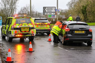 NANTGARW, NEAR CARDIFF, WALES - FEBRUARY 2020: Traffic officers helping a motorist after a road closure due to flooding in Nantgarw near Cardiff