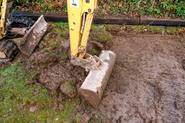 CARDIFF, WALES - JANUARY 2020: Close up of the bucket of a mini excavator digging up the lawn in the back garden of a residential property