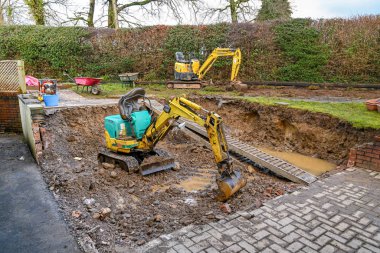 CARDIFF, WALES - FEBRUARY 2020: Mini excavators in the back garden of a residential property excavating earth for a patio.