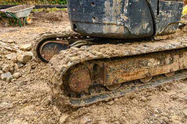 CARDIFF, WALES - FEBRUARY 2020: Mud covered crawler tracks of a mini excavator in the back garden of a residential property