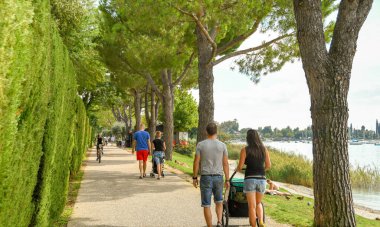 EN ROUTE GARDA TO BARDOLINO, LAKE GARDA, ITALY - SEPTEMBER 2018: People walking along the path around Lake Garda from Garda to Bardolino