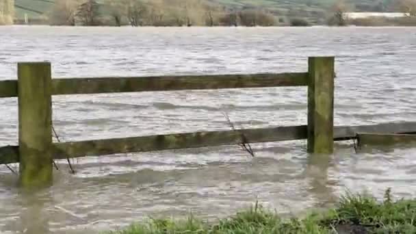 Clôture en bois submergée par des eaux d'inondation boueuses après des conditions météorologiques extrêmes 