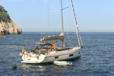 CAPRI ADASI, İTALYA - 2019 AĞUSTOS: Capri Adası 'nın maliyeti dışında bir yatta bulunan bir grup insan.