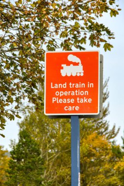 Sembollü ve yazılı kırmızı ve beyaz tabela insanları bölgede bir kara treninin çalıştığına dair uyarıyor.