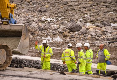 PORTHCAWL, WALES - Haziran 2018: İnşaat işçileri dış görünüşünü iyileştirmek ve deniz savunmasını güçlendirmek için Porthcawl 'daki deniz kenarındaki kayalara beton döşüyorlar.