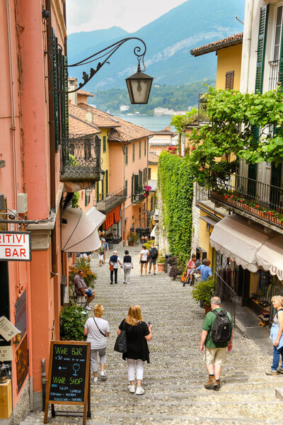 BELLAGIO, LAKE COMO, ITALY - JUNE 2019: People shopping in a steep, narrow, street in Bellagio on Lake Como.