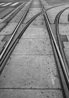 Dümdüz giden ya da sağa doğru dallanan rayları olan bir kavşaktaki siyah beyaz tramvay manzarası. Kopya için yer var. Kimse yok..
