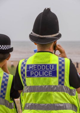 Swansea, WALES - Temmuz 2018 Swansea sahilinde devriye gezen erkek ve kadın polis memurları.