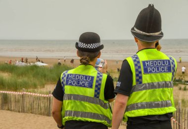 Swansea, WALES - Temmuz 2018 Swansea sahilinde devriye gezen erkek ve kadın polis memurları.