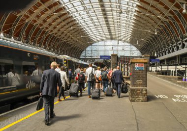 Londra Paddington İstasyonu 'ndaki bir platformda yürüyen ve platform numarası açıklandıktan sonra trene binen insanların geniş açılı görüntüsü. Bazıları bavullarını çekiyor..