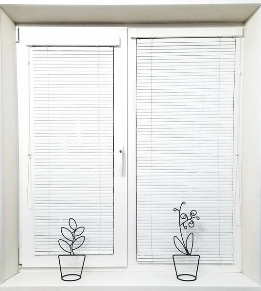 White horizontal blinds on new plastic windows. Design and repair of premises, the concept of window repair. Indoor plants in the interior.