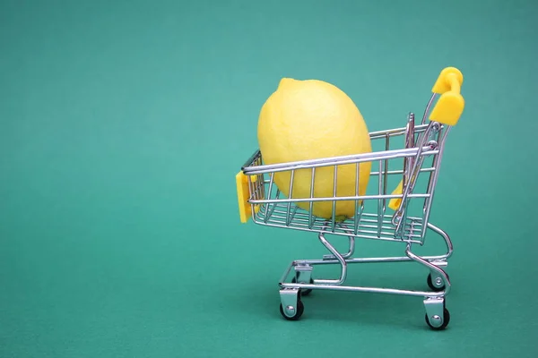 Citron i kundvagnen är isolerad på en grön bakgrund. Begreppet hälsa och vitaminbehandling. — Stockfoto