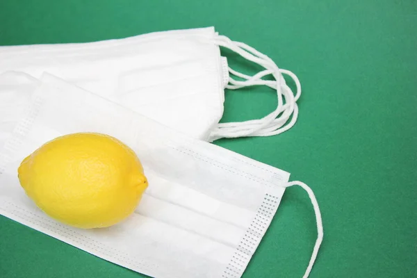 Un limón amarillo se encuentra en una pila de máscaras médicas. Medicina y asistencia sanitaria . — Foto de Stock