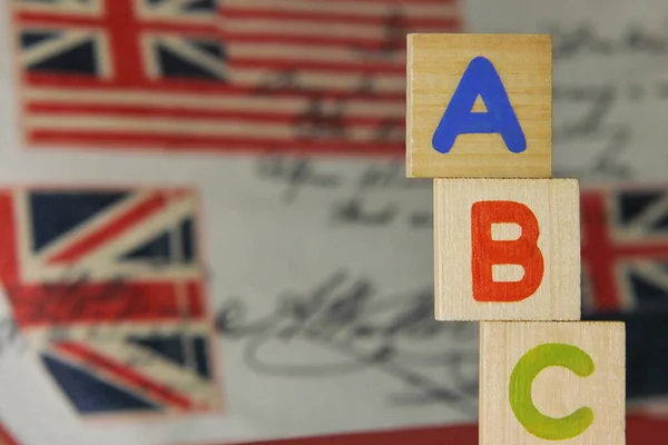 ABC-letters of the English alphabet on wooden cubes on the background of images of the English flag. Learning foreign language. English for beginners.