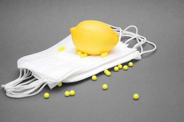 一个黄色的柠檬躺在一堆口罩上.抗坏血酸维生素散布在附近. — 图库照片